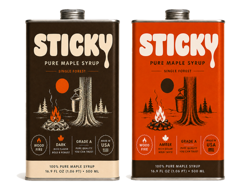 Two large tins of Sticky pure maple syrup side by side, a dark brown Dark tin and an orange-red Amber tin