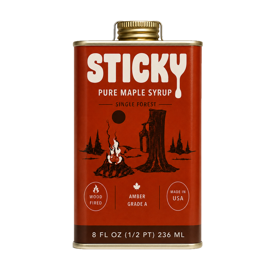 Brick-red 8 oz tin of Sticky Amber maple syrup with a gold cap, cream logo, drawn campfire and maple tree