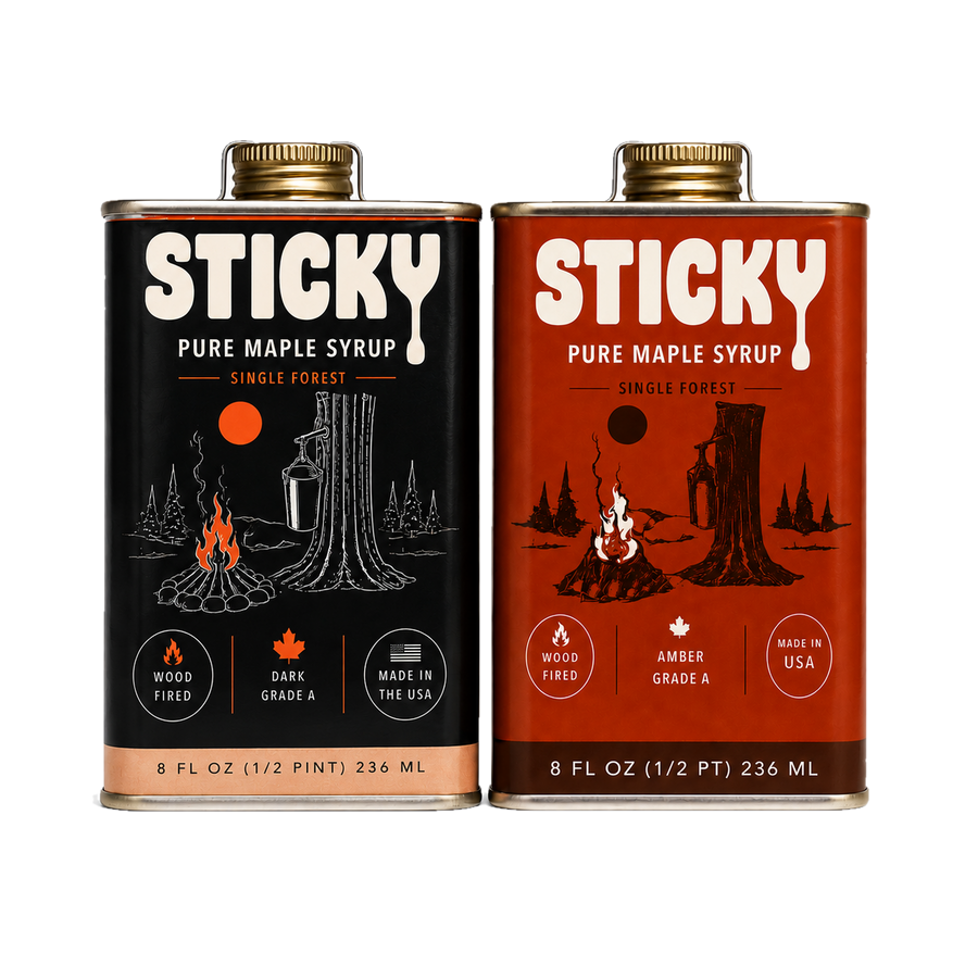 Two 8 oz tins of Sticky pure maple syrup side by side, a black Dark tin and a brick-red Amber tin